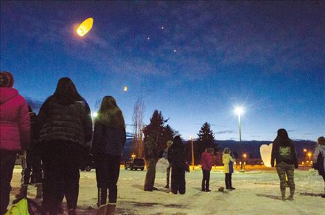 Students and community members watch as lanterns float above the baseball field.