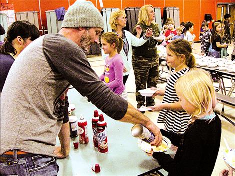  Parent volunteer Chris Dubuque puts whipped cream on ice cream for students. 