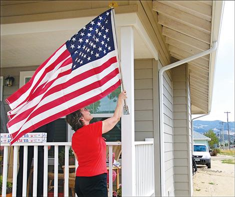 The owner of a newly-finished home in an affordable housing project in Boulder raises the flag on dedication day.