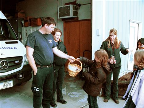 Gracie Heiner gives a gift basket to paramedic Greg Sheumaker and emergency medical technician Emily Neader last week. 