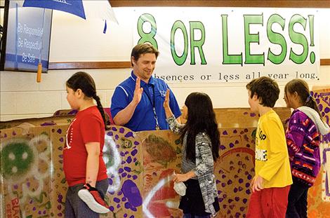 From a large decorated box, Principal Tyler Arlint high-fives students for reading thousands of books in February.