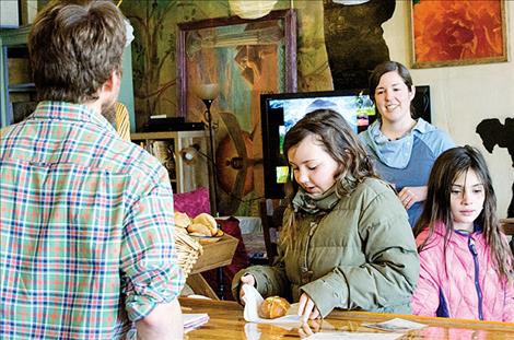 Shay Farmer watches as two customers purchase the bread rolls she made fresh.