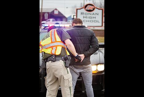 A highway patrol officer handcuffs a mock suspected drunk driver during a Ghost Out event.