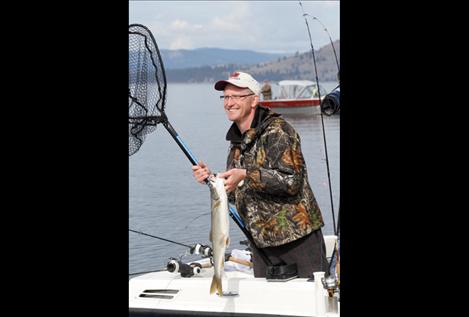 A beaming Mack Days angler volunteers a freshly-caught lake trout to CSKT officials so it can be tagged and released elsewhere.