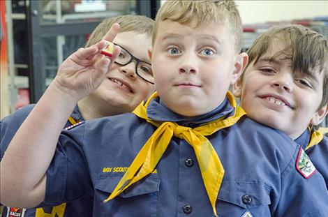 Nate Alder, 8, holds up an example of a uniform belt buckle the scouts will earn for holding the food drive.