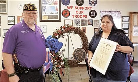 District Commander Glen Sharbono, the wreath, and Rocky Davis holding her certificate, which reads: This certificate of appreciation is gratefully presented to Raquel Davis in recognition and sincere appreciation of outstanding service and assistance, which contributed to the advancement of The American Legion  programs and activities dedicated to God and Country. For the heartfelt wreath she made at the request of the District No. 4 Commander to be presented at the “Healing Wall.” Presented by District No. 4,  Department of Montana, “Thank you Rocky.” 