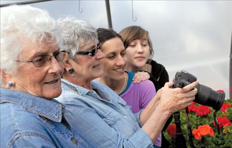 Four generations of gardeners check out their picture in the greenhouse. Lois Shore, her daughter Kathy Shore, Kathy’s daughter Kari Wise, and Kari’s niece Ursula Wise, all have great skin from the moist, plant-filled building and good genes.