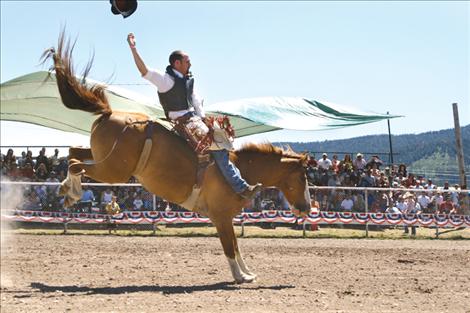 A bareback rider loses his hat just before being bucked off.