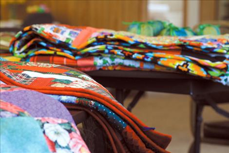 Recently sewn blankets and quilts of varying size, texture and color await new owners.  
