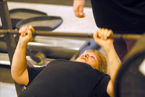 Virginia Cornelius works on her bench press at her son’s home gym in Ronan. Cornelius has been strength training since 2003. 