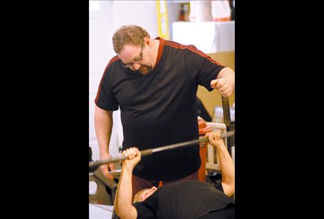 James Greene spots mom Virginia Cornelius as she works out on the bench. Cornelius recently set a new state record for dead lift in her age group.