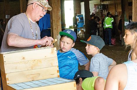 Chuck Lewis shows kids how a wooden bee hive is put together. 