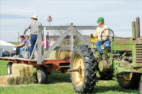 Curt Rosman drives a tractor while Sigurd Jensen talks to the kids about local weeds.