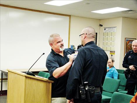 Polson Police Chief Wade Nash pins the corporal badge onto Corporal Mathieu Gfroerer during last week’s Polson City Commission meeting.