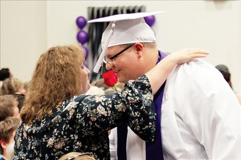 Charlo graduate Dylan Stevens shares a rose and a hug with a loved one.
