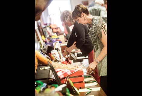 Janet Caselli, who helped organize the fundraiser with husband David, below, looks through a wall of donated auction items.