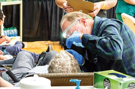 A Salish Kootenai College dentist checks to see if a woman has any dental issues at one of the booths.