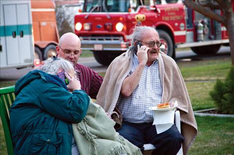 Homeowners Barbara and Lucky Donnegan are comforted by neighbors as they watch a fire consume their home of 28 years.