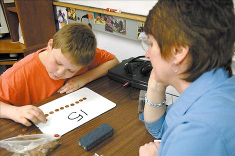 An 11-year-old Jake counts pennies in April 2005 with his former tutor MichalAnn Stedje. Eight years later, Jake is preparing to graduate this spring with his classmates.