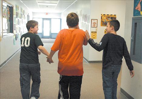 A couple of Jake’s classmates lead him down the hallway to play outside in April 2005. Jake’s classmates have supported and protected Jake during their school years.