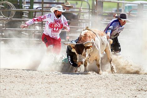 Rob Zolman/Valley Journal Lil’ Red drags rider Carnell Smith as bullfighters Austin Wagner and Bo Herak race to his rescue.