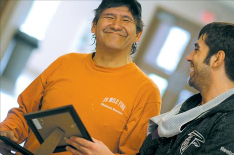 Alonzo Brings Yellow Sr. and Bo Herak laugh and joke while looking at photos of the FUPS teams. Part of a team’s entry fee goes toward a team portrait which players leave on the table until Sunday.