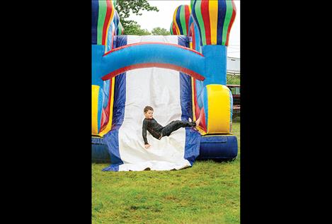 A boy plays on the bouncy slide while the rain pours down. 