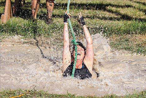 Nicole Kramer takes a muddy plunge on the rope swing obstacle.