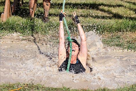 Nicole Kramer takes a muddy plunge on the rope swing obstacle.