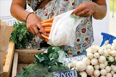  A shopper gathers homegrown food from the St. Ignatius farmers market.
