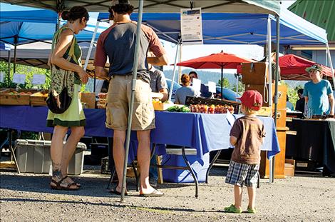 People enjoy recently-picked tomatoes, carrots, greens and other farm-fresh foods as well as  handcrafted items available at the market.