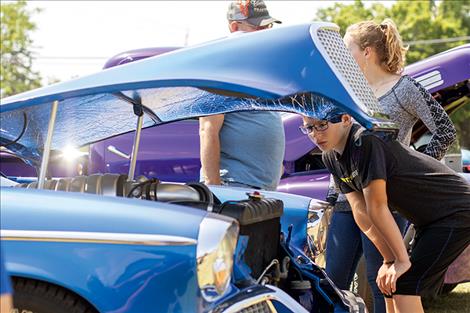 A teen takes a peak under the hood during the car show on Saturday.
