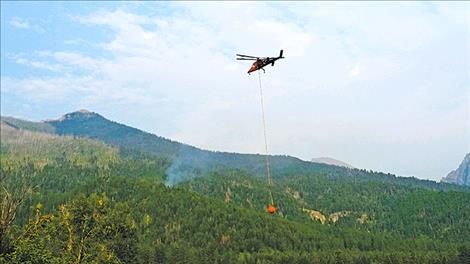 A small plume of smoke remains after several buckets of water are dropped on the fire.