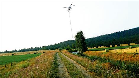 A helicopter bucket dips into an irrigation ditch on the Biggs Ranch.