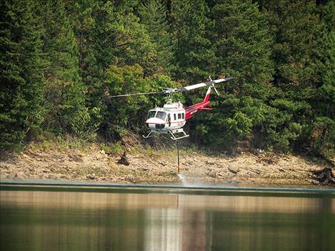 Another helicopter drops water on the scene.