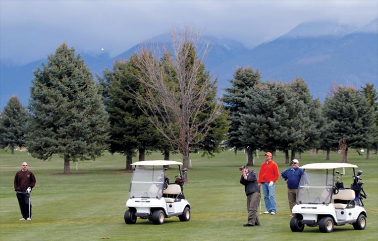 Members of “Tie Dye Muscle,” one of 20 teams in Saturday’s CASA fundraising golf tourney in Polson, watch as  teammate Aaron Auclaire of Kalispell takes a swing. Entry fees, donations and the proceeds of a silent auction support Court Appointed Special Advocates for Children in Lake County. The tourney also offered an auction where players could bid on local celebrities to join their team.   