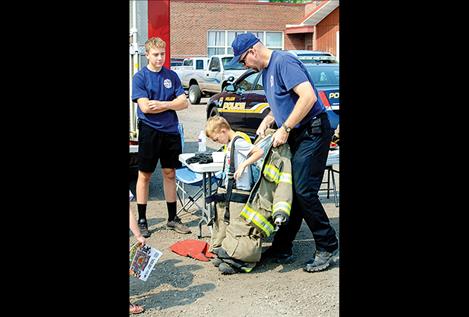 Lt. James McKee with the Polson City Fire Department helps a child try on the gear firefighters wear.  