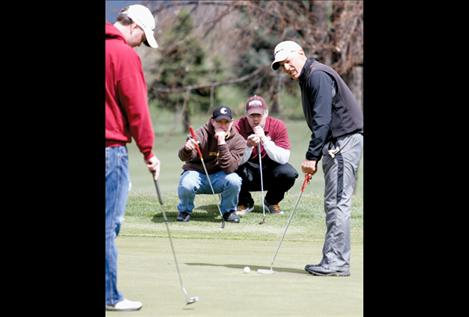 Ron Fricker of Polson lines up a putt during the CASA Scramble April 20 as Brad Walter, left, Chad Komlofske and Billy Fisher watch.