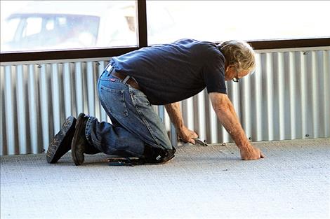 A volunteer installs carpeting Friday for the Boys and Girls Club as part of Community Build Day.