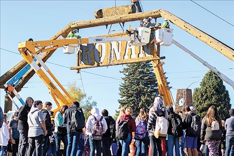 Members of the Ronan community watch the sign being taken down from the arch.