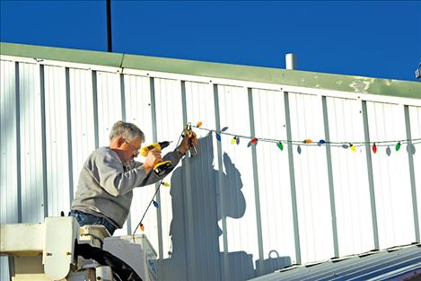 Jay Preston hangs part of thousands of Christmas lights at the Ronan Fairgrounds for the upcoming Lights Under the Big Sky event.