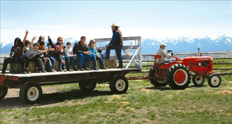 John Campbell drives Gil Mangels’ 1937 Allis Chalmers tractor pulling a load of fourth graders from Linderman Elementary School. Sigurd Jensen stands on the wagon and tells kids about the types of grass and what cows eat. Campbell is an associate supervisor and Jensen a supervisor with the Lake County Conservation District that hosted Ag Days.