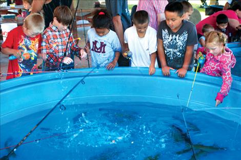 A reluctantly hooked trout splashes a group of eager young anglers.