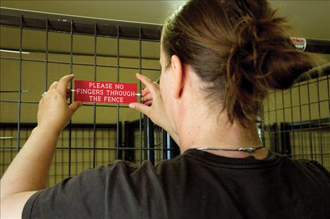 Beth Pecora, a member of SKC’s nursing faculty, affixes a new sign on a kennel inside Mission Valley Animal Shelter, instructing visitors not to put their fingers through the fencing.
