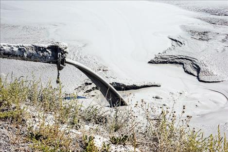 A pipe pours coal ash into a pond at Montana’s Colstrip  power generating facility.
