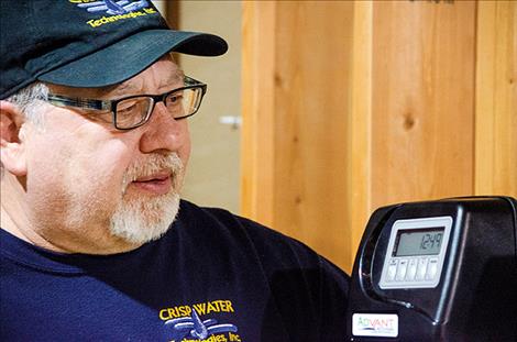 Certified Water Specialist Ken Crisp looks at the arsenic filtration system he set up in Tom Vaughn's home.