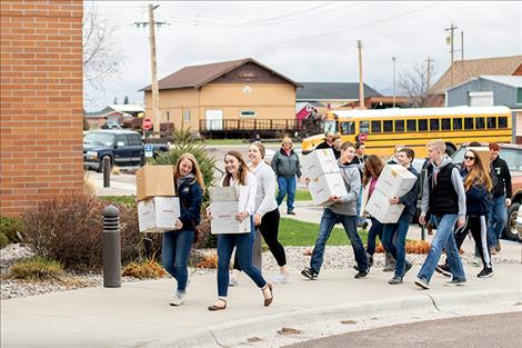 students carry boxfulls of blankets in the hospital.