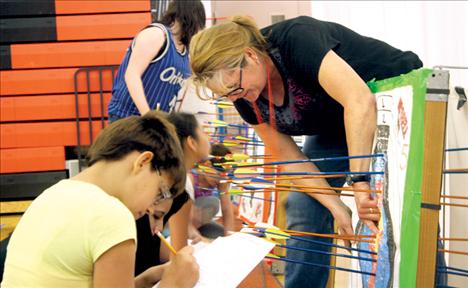 Ronan Middle School teacher Crystal Pitts shows Jodi Burland how to properly score one of her shots. 