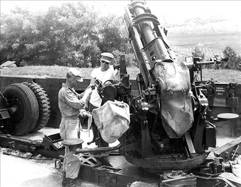 Staff Sgt. Charles "Chuck" Whitson works on weaponry in a white T-shirt and sunglasses during the 1950s.