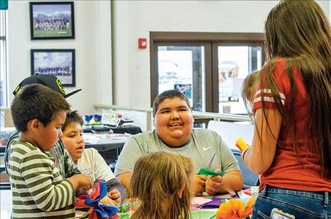 Annalysia  DuMontier helps  younger students  create paper flowers.